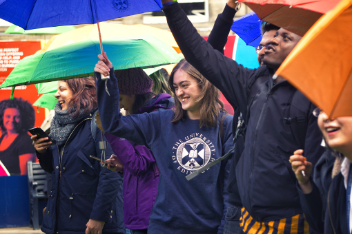 Students laughing in the rain, under umbrellas at University of Edinburgh Welcome Week